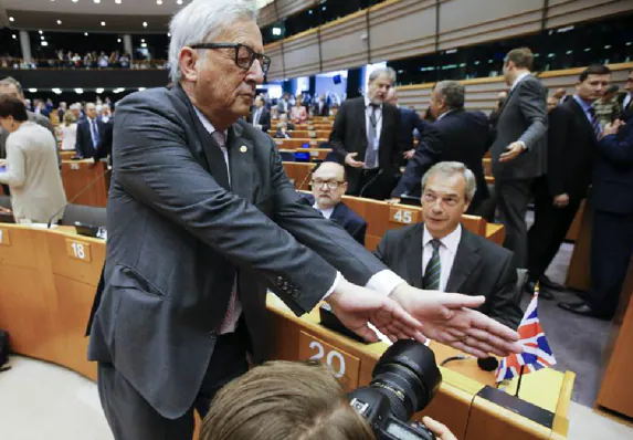 Juncker tapa la cámara a un fotógrafo que enfoca al líder del Partido de la Independencia de Reino Unido, Nigel Farage.