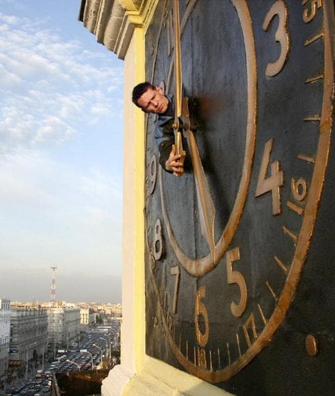 Un hombre manipula el reloj de la ciudad.
