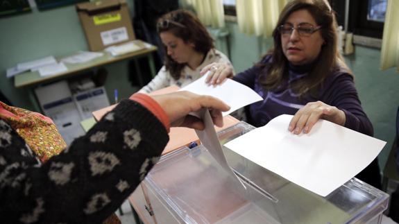Una mujer deposita su voto en la urna, en una mesa electoral de Madrid. 