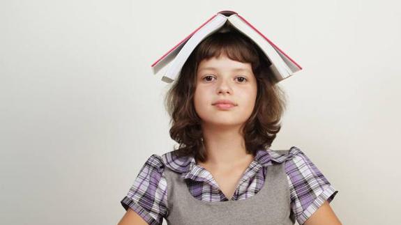 Una estudiante, con un libro encima de la cabeza.