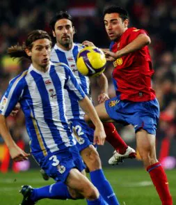 Xavi intenta llevarse el balón ante el brasileño Filipi Luis. / EFE