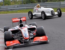 Lewis Hamilton conduce un antiguo Mercedes de carreras y pasa junto a su McLaren. /EFE