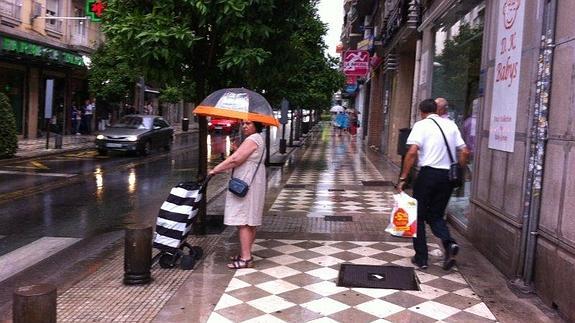 Una mujer se protege de la lluvia con un paraguas en pleno centro de Granada  