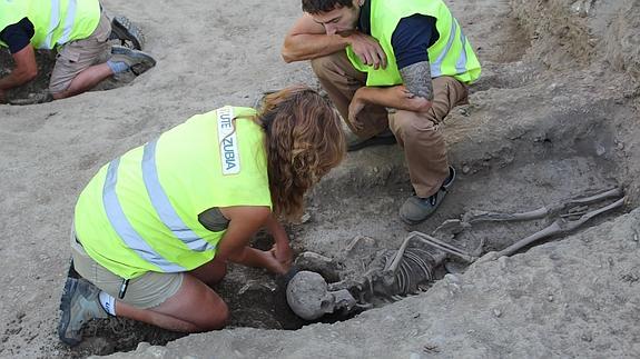 La arqueóloga responsable de la excavación retira tierra de debajo de uno de los cuerpos antes de levantar el cráneo. 