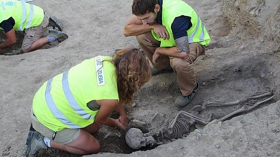 La arqueóloga responsable de la excavación retira tierra de debajo de uno de los cuerpos antes de levantar el cráneo.