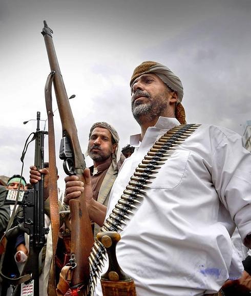 Chiíes-hutíes alzan sus armas y gritan consignas durante una protesta por los bombardeos suníes en Saná, Yemen. 