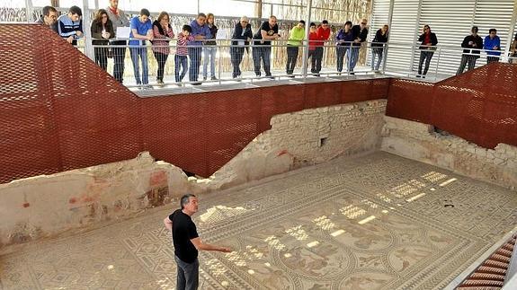 Visitantes en el yacimiento arqueológico de Cástulo observan el Mosáico de los Amores 