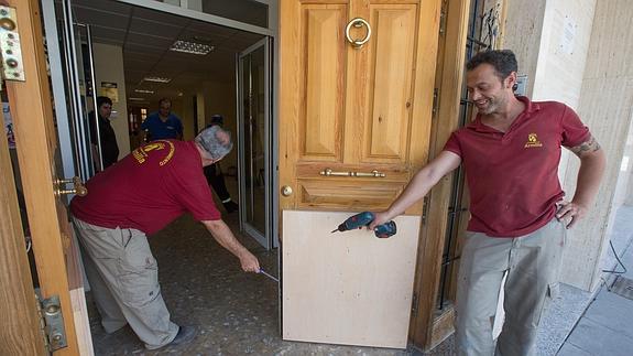 Operarios municipales arreglando los desperfectos de la puerta del Consistorio armillero