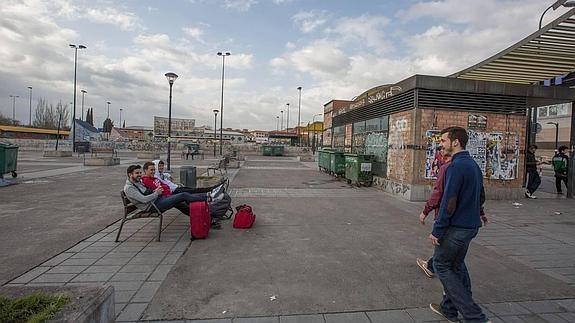 Jóvenes esperan sentados en un banco a otros que llegan al recinto del botellódromo