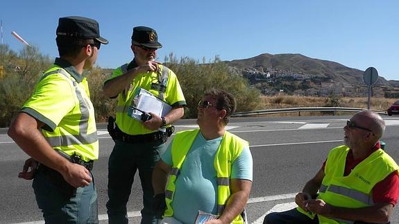 Francisco y Enrique, miembros de la asociación Aspaym, charlan con dos guardias civiles en el control de velocidad.