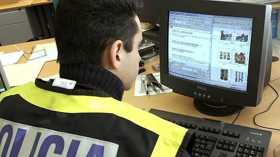 Un policía nacional examina unas imágenes a través de un ordenador incautado a un detenido