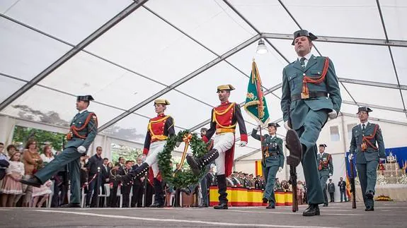 Agentes portan la corona para su colocación en la peana del monumento a los caídos.