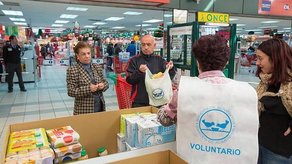 Voluntarios, en un centro comercial recogiendo alimentos de clientes solidarios.