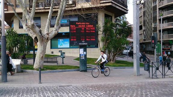 Un joven paseaba ayer con su bicicleta junto al panel informativo sobre la calidad del aire en la capital.