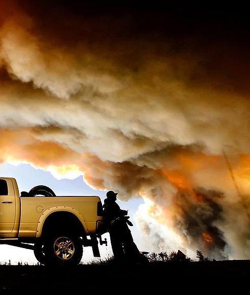 Un bombero se toma un descanso mientras contempla el fuego que ha arrasado la ciudad canadiense de Fort McMurray, que sigue sin poder ser controlado. 