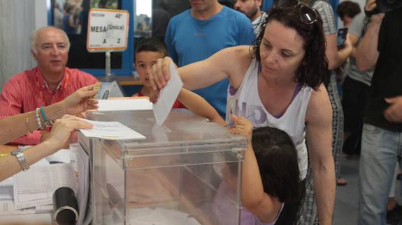 Una mujer vota en la capital con ayuda de una menor. 