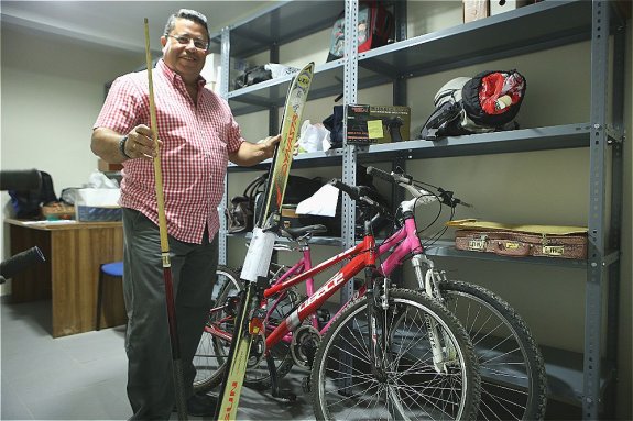 Julián Montero sujeta un juego de esquís y un taco de billar ante bicicletas y otros objetos perdidos.