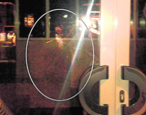 La silueta de un cochero aparece en una imagen tomada sobre el cristal de la puerta del sótano.