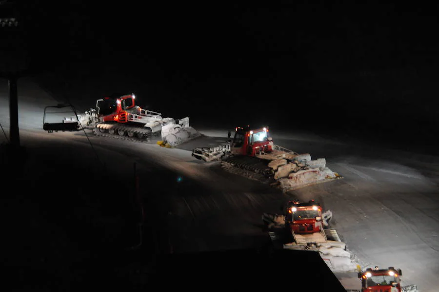 Máquinas ‘retrac’ trabajan en horas nocturnas distribuyendo y aplanando la nieve en las pistas de una estación de esquí.
