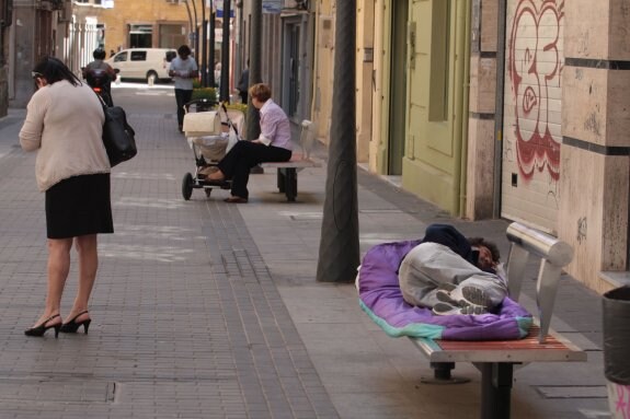 Un hombre duerme en un banco en una céntrica vía de la capital almeriense.