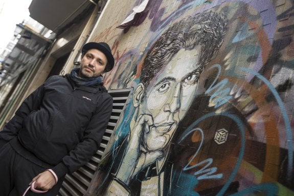 El artista Christian Guémy, C215, ante su retrato de Lorca pintado en una céntrica calle.