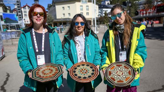 Tres voluntarias muestran las bandejas que se utilizarán en la entrega de medallas.