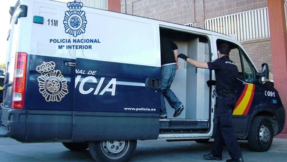 Un agente de la Policía Nacional introduce a un detenido en un furgón.