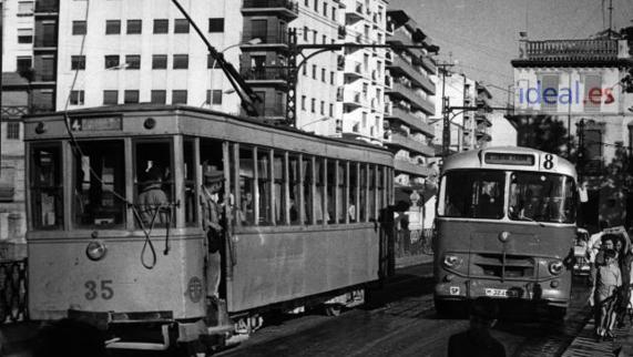 Fotografía de archivo de un tranvía cruzando el puente del Río Genil. A su lado uno de los primeros autobuses urbanos. 1970 