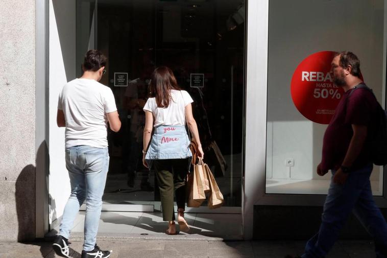 Clientes entran en una tienda salmantina con el cartel de rebajas.