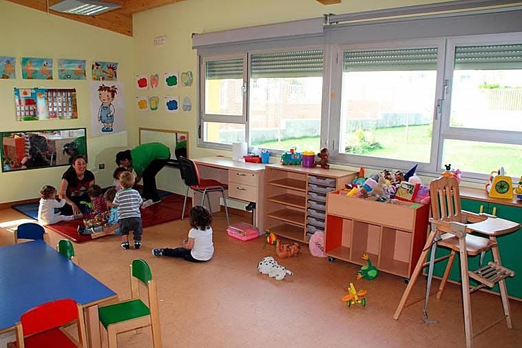 Monitoras atendiendo a varios niños en una escuela infantil.