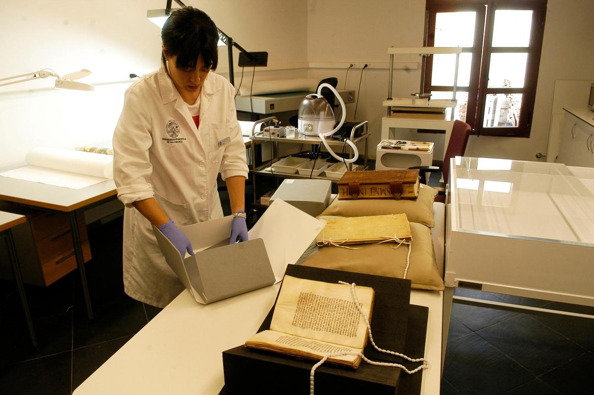 Katia Martín Polo entre los libros, las cajas y herramientas del taller de restauración de la Pontificia.