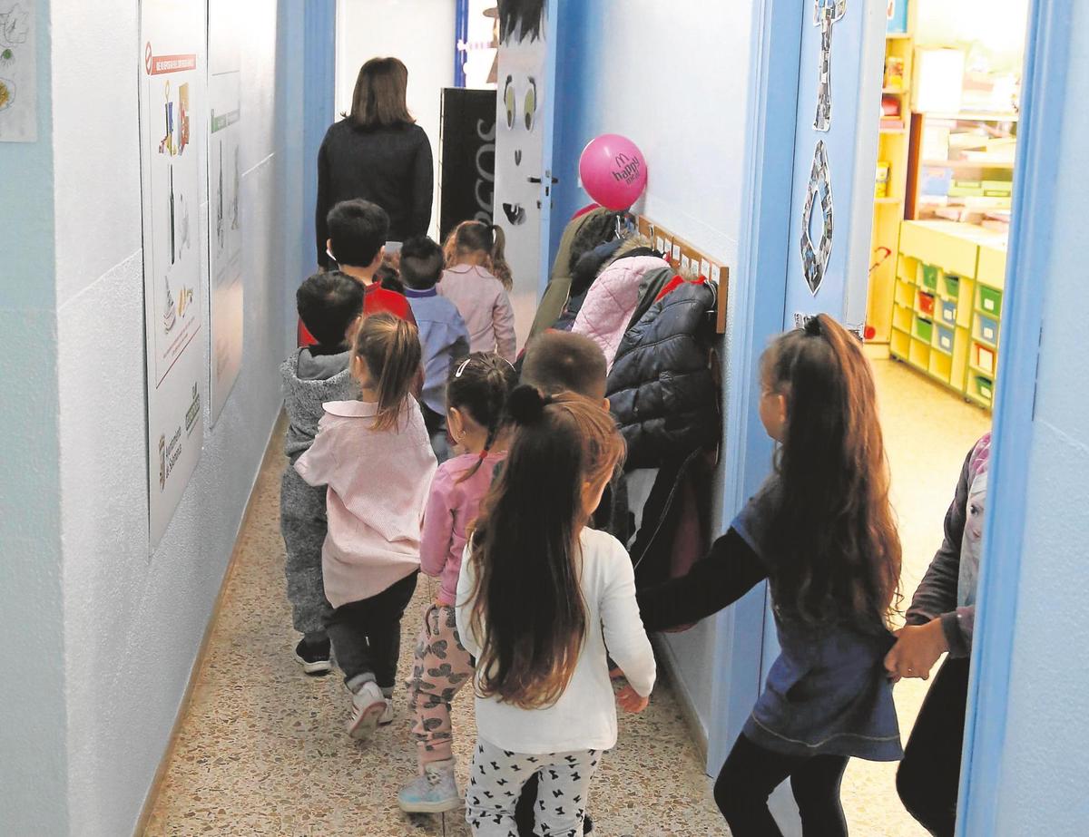 Una maestra de Infantil conduce a los niños de un colegio a otra estancia del centro.