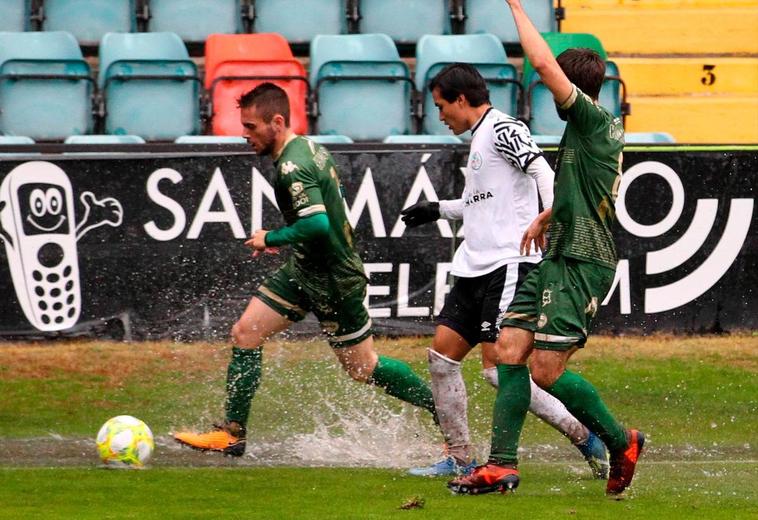 Monárrez pelea el balón ante dos rivales en una zona encharcada.