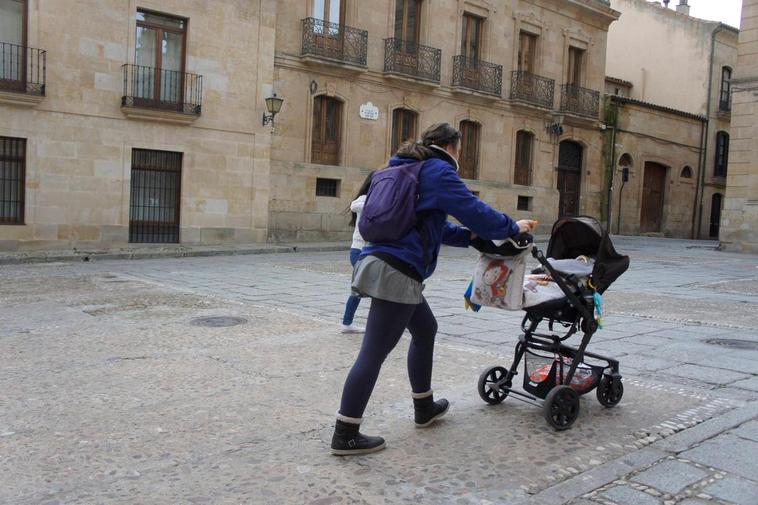 Una madre empuja el carrito con su bebé en las calles de Salamanca.