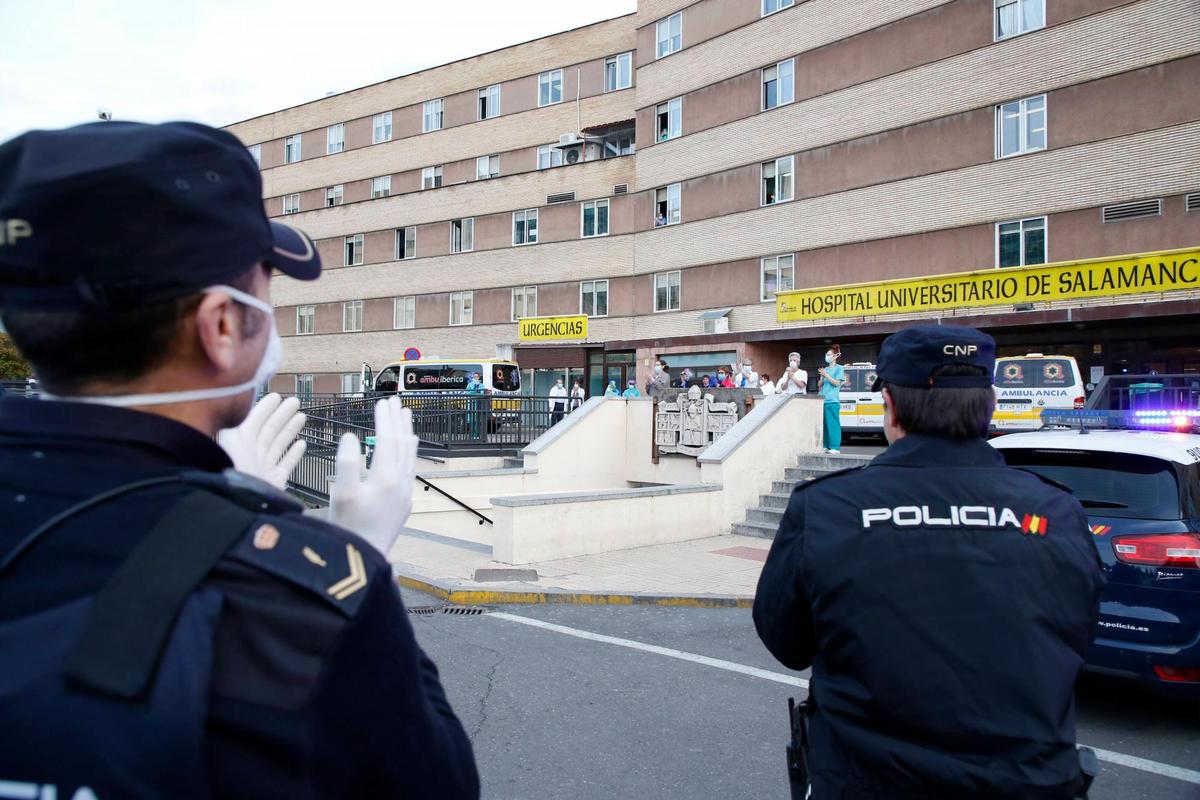 Dos policías aplauden a los sanitarios ante el Hospital de Salamanca.