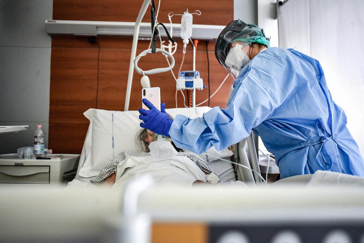 Un médico sujeta un móvil mientras un paciente habla con un familiar.