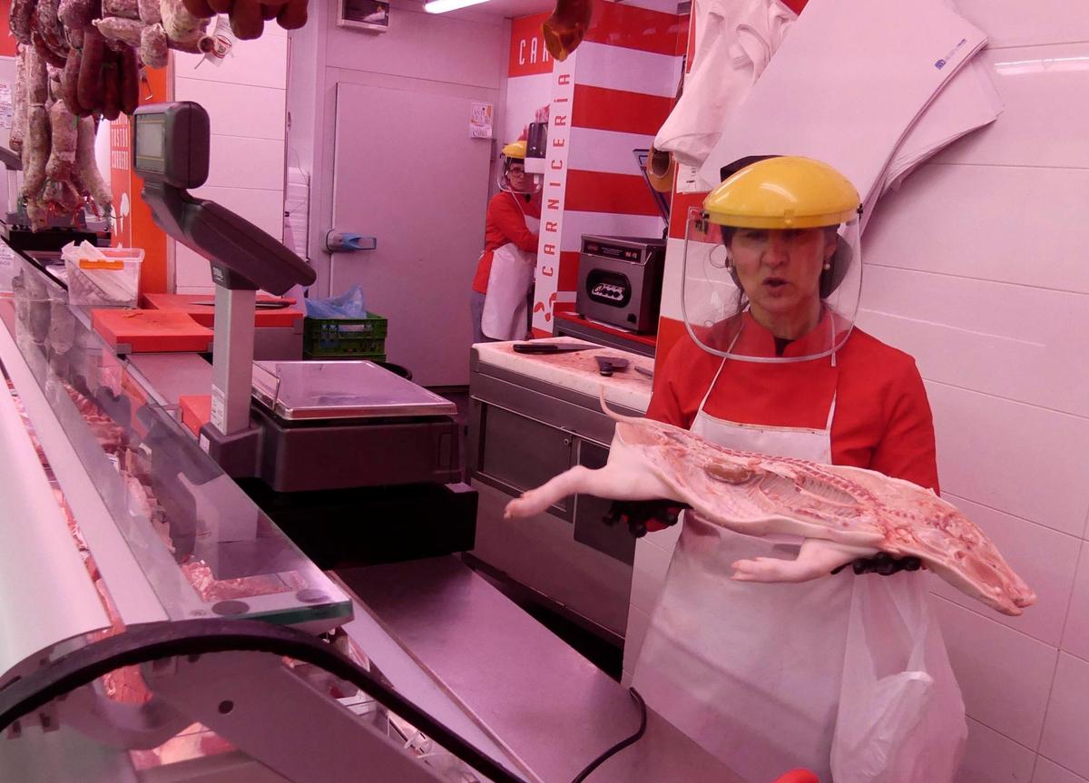 Choni muestra media pieza de tostón en su carnicería del Mercado de San Juan.