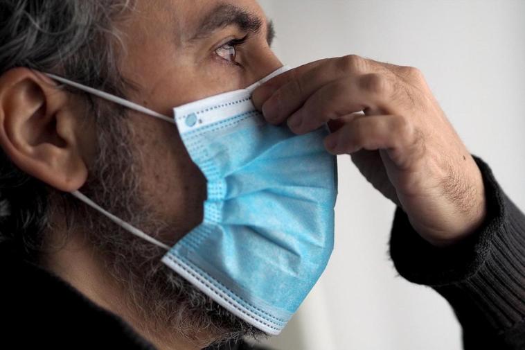 Un hombre ajustándose una mascarilla.