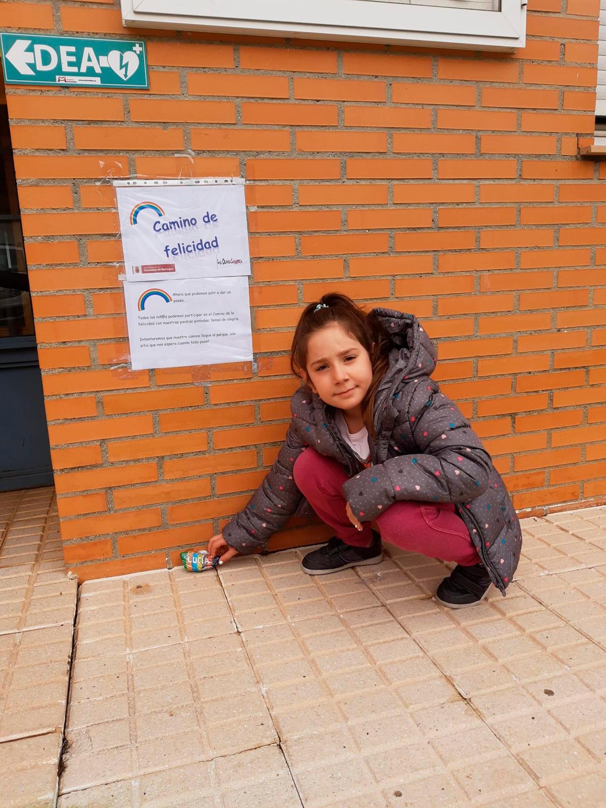 Una niña deposita su piedra decorada con su nombre en el inicio del ‘camino de la felicidad’.