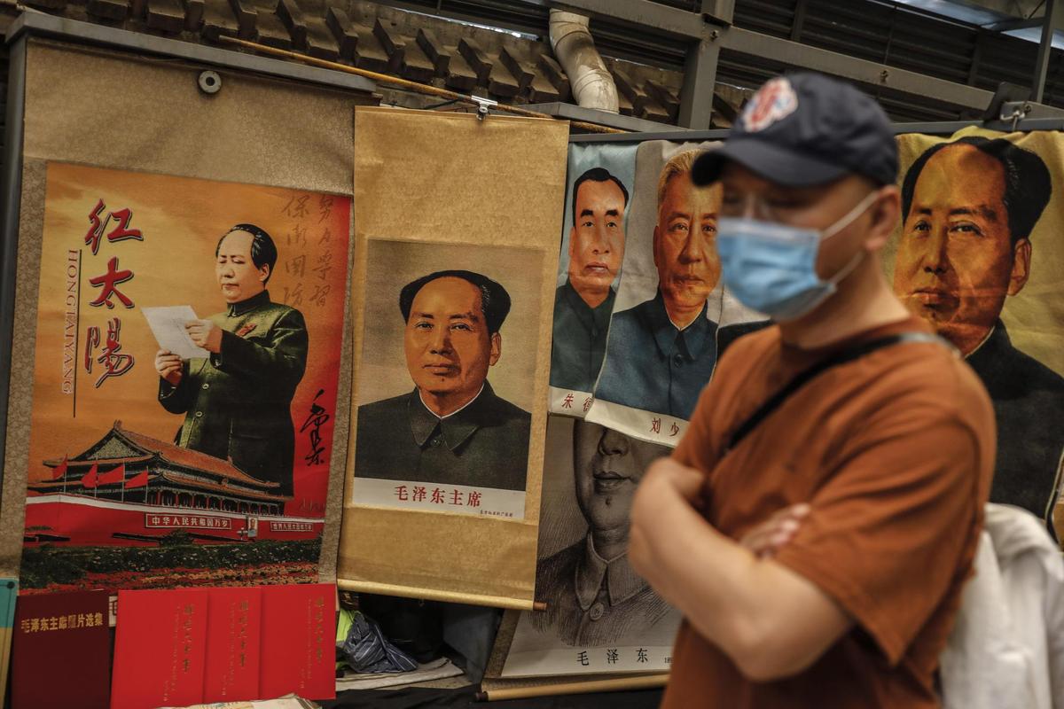 Un ciudadano chino pasa ante carteles propagandistas de Mao Zedong.