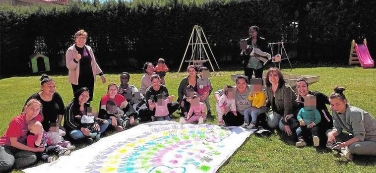 Rosario Álvarez (de pie izda.), directora del centro, con las madres y sus hijos en el jardín.