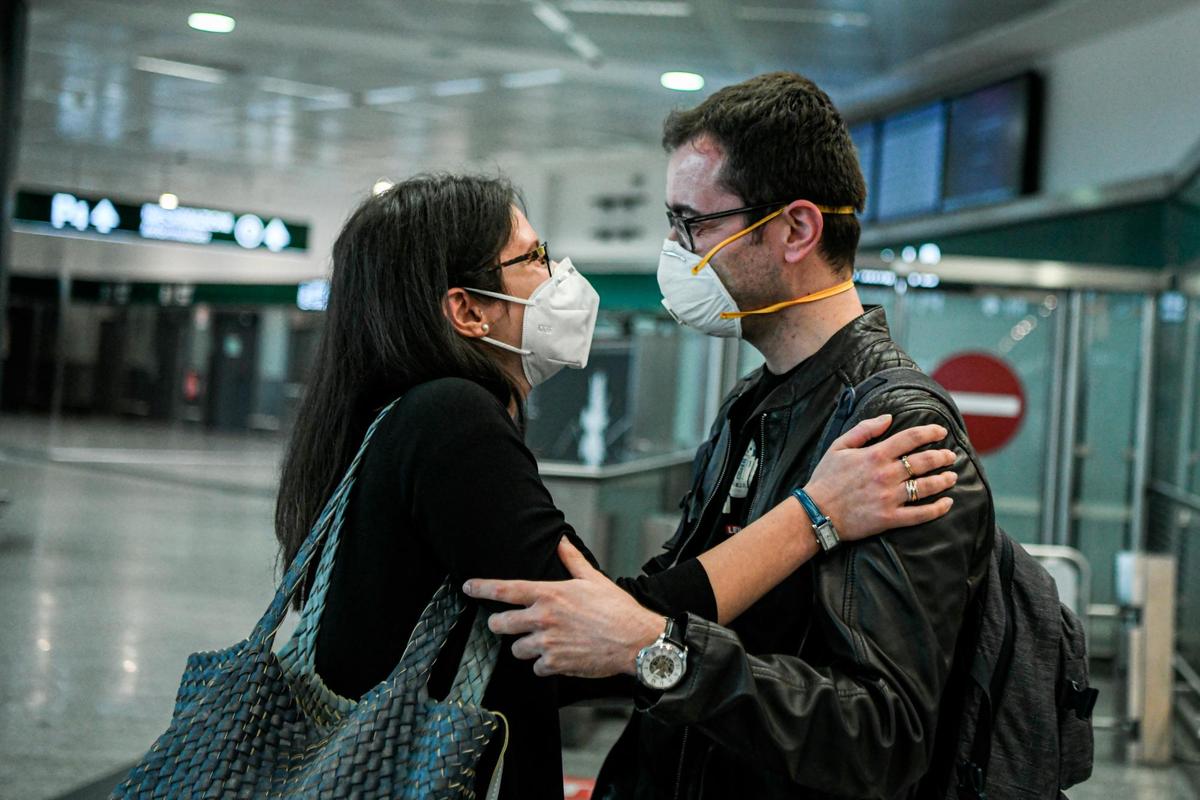 Una pareja con mascarilla en un aeropuerto.