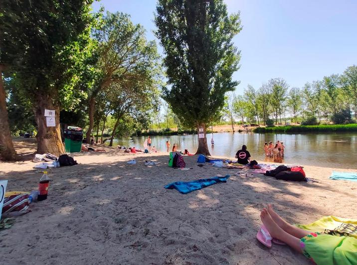 Grupos de bañistas a orillas del río Tormes a su paso por la localidad de Huerta.