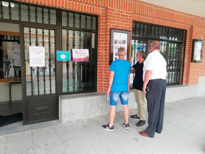 Vecinos observando las fotografías de los jóvenes candidatos.