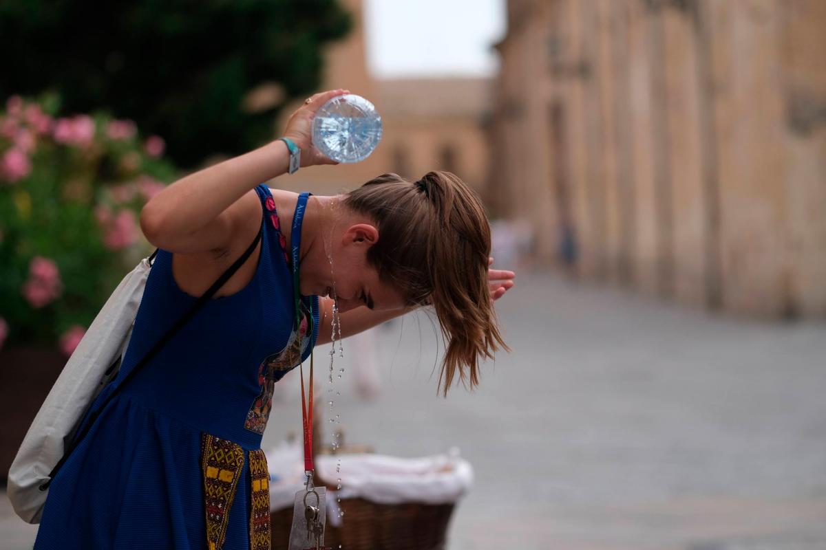 Una chica se refresca con una botella de agua en la calle