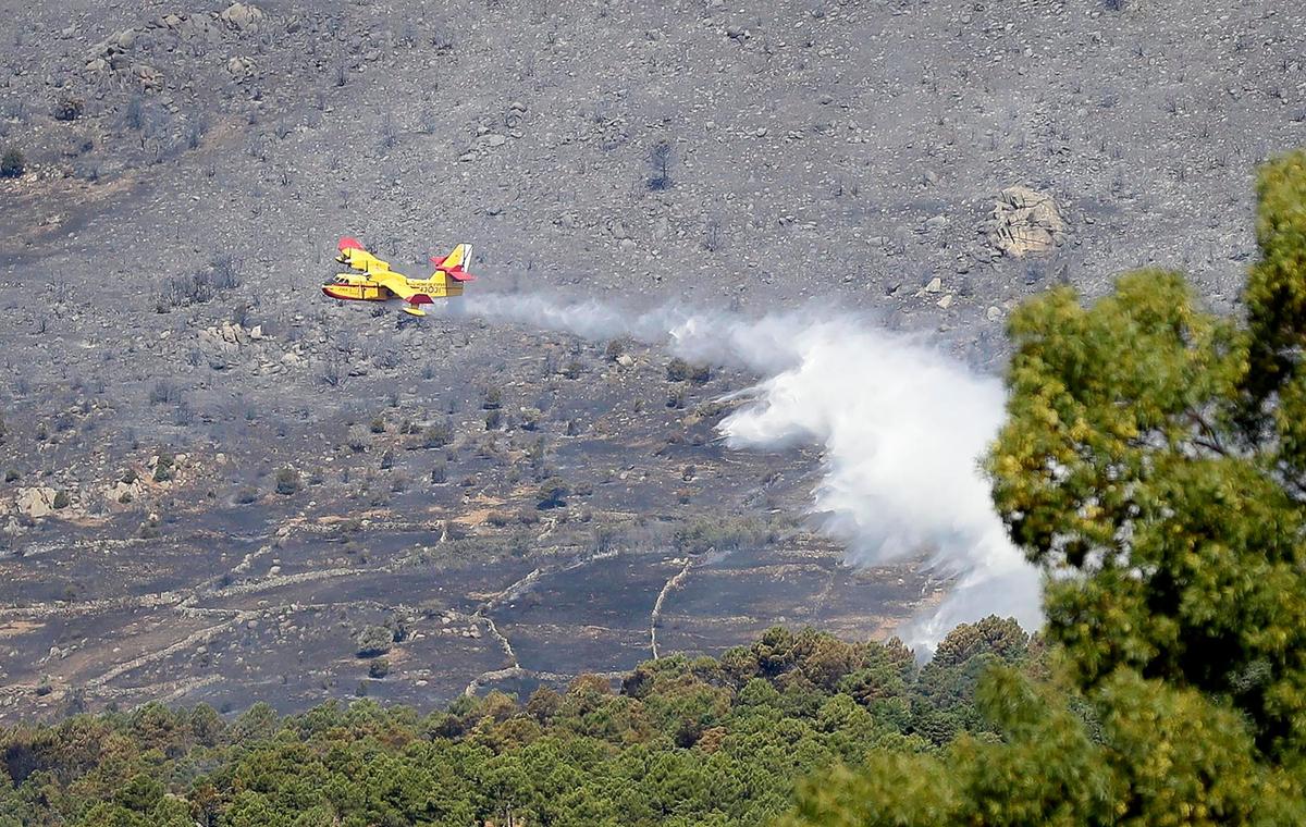 Un avión apaga incendios de la Unidad Militar de Emergencias (UME) vierte agua sobre el incendio forestal.