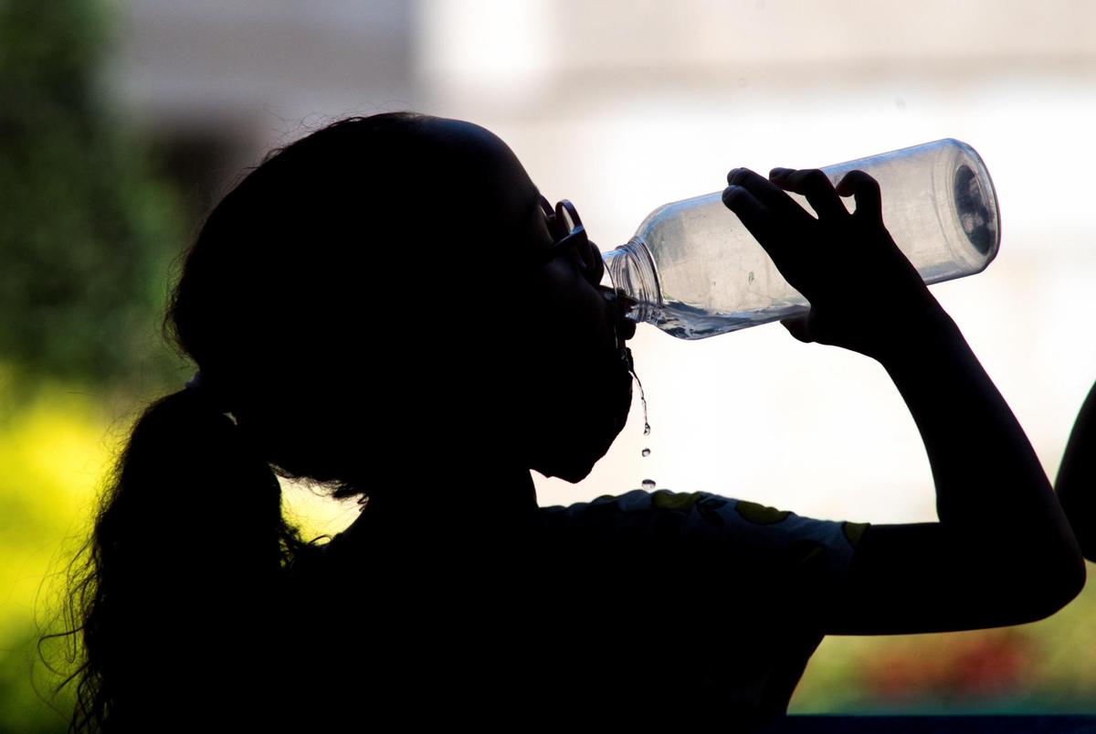 Una niña bebe agua.