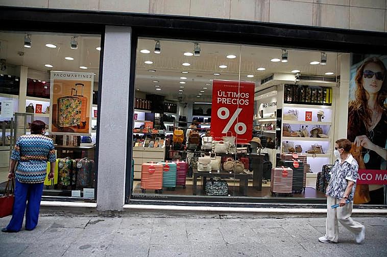 Una mujer, mirando el escaparate de una tienda de maletas y bolsos.