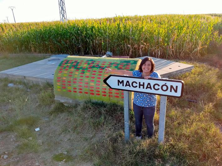 La artista Puerto García Sierra junto a una de sus creaciones en un bloque de tubería a la entrada del pueblo.