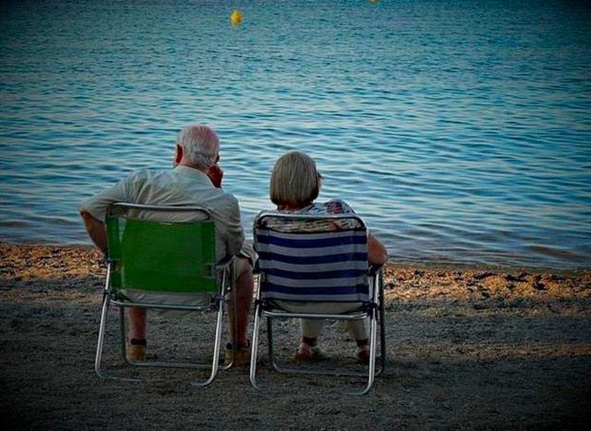 Dos personas mayores miran al mar en un viaje del Imserso